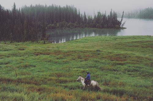 Woman riding a horse near a lake