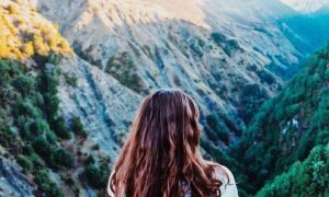 woman facing backward watches beautiful hills