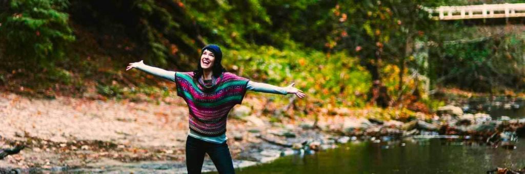 woman excitedly happily standing besides lake gratitude life in forest