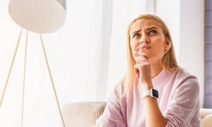 woman sits on couch beside lamp thinking making decision