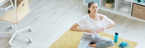 woman sits on yellow rug focusing on breathing meditation practicing calmness