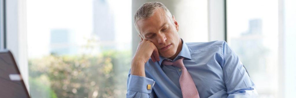 businessman sits hand on cheek tiredly sleeping in office