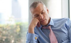 businessman sits hand on cheek tiredly sleeping in office