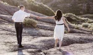 couple walks on rocks holding hands