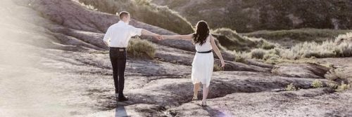 couple walks on rocks holding hands