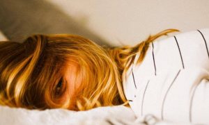woman tiredly lies on bed having difficulty to sleep