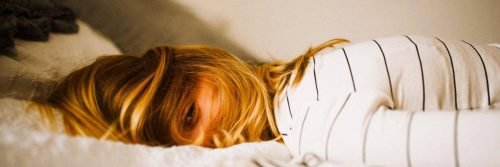 woman tiredly lies on bed having difficulty to sleep