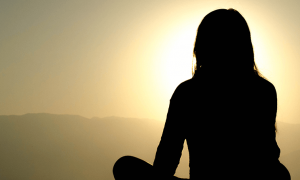 woman shadow sits leg crossed concentrates on meditation in sunny sky