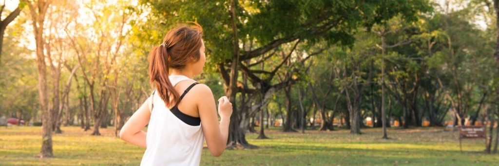 woman exercises jogs in park in beautiful sunny weather