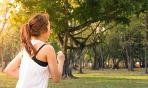 woman exercises jogs in park in beautiful sunny weather