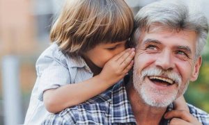 grandfather happily laughs listens to grandson whispering to his ear