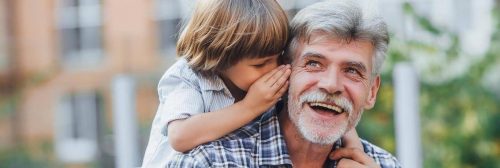 grandfather happily laughs listens to grandson whispering to his ear