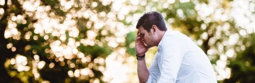 man sits hand in face feeling sad worried painful overthinking