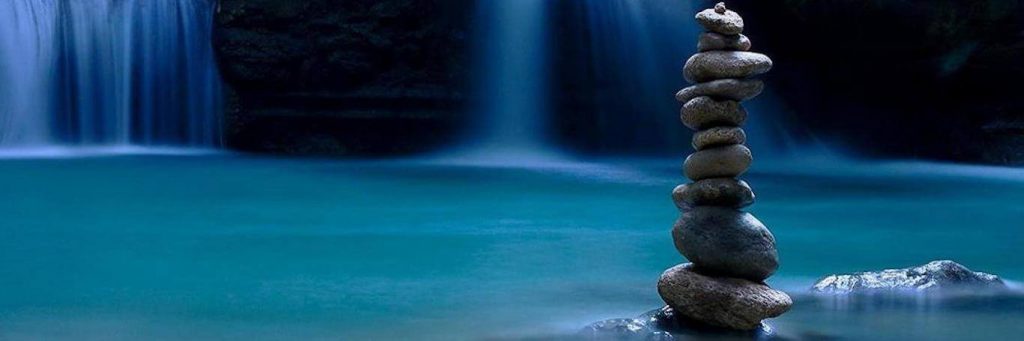 balanced stones on rock beside waterfall