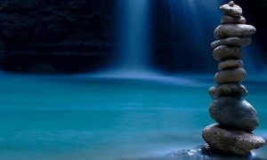 balanced stones on rock beside waterfall