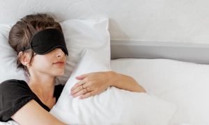 woman covering eyes white mask hugs white pillow sleeping