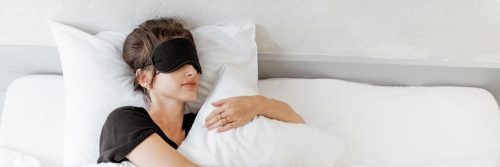 woman covering eyes white mask hugs white pillow sleeping