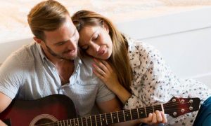 man playing guitar while girlfriend lying on shoulder listening