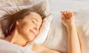 elderly woman lying on bed sleeping tightly on white pillows