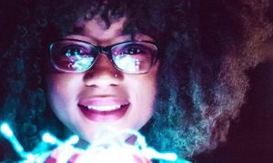 curly black hair woman happily smiles carrying lighting bulbs