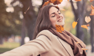 woman wearing scarf stand nearby forest gratitude fall leaves flying