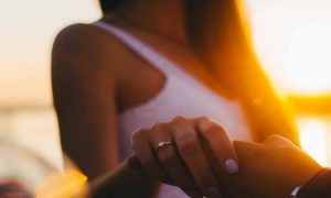 woman wearing ring holding partner hand in sunny sky