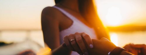 woman wearing ring holding partner hand in sunny sky