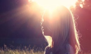 woman stands under shining sun thinking