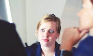 woman looks at two colleges talking in office