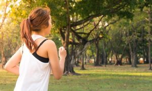woman exercises jogs in park in sunny sky