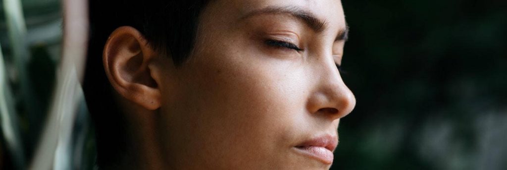 woman closing eyes focuses on breathing eliminating negative thoughts