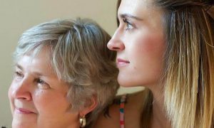 mother sits with daughter happily smiling