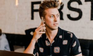 man sits in busy coffee shop answering phone