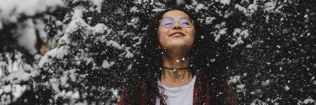 woman enjoyably stands under tree filled with snows