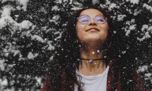 woman enjoyably stands under tree filled with snows