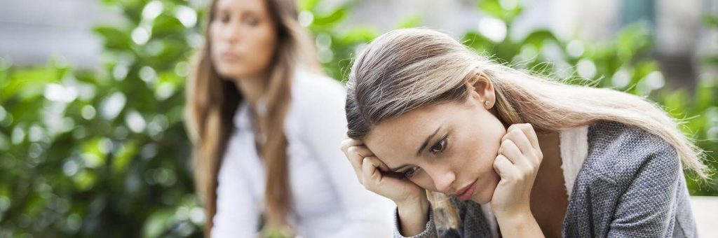 woman sits feeling sad hurt while lady looking at her