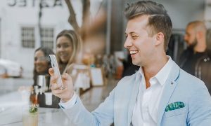 businessman stands outside crowded shop talking on phone smiling happily