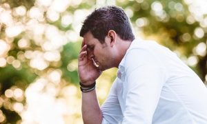 man sits hand in face feeling sad worried painful overthinking