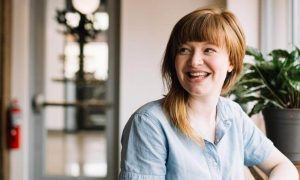 woman sits alone in coffee shop smiling