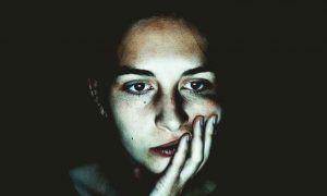 woman sad depressing face hand in face upset in dark