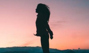 woman shadow stands enjoying cool weather in sunset sky