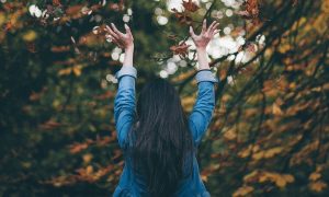 woman stands in forest facing backward gratitude life