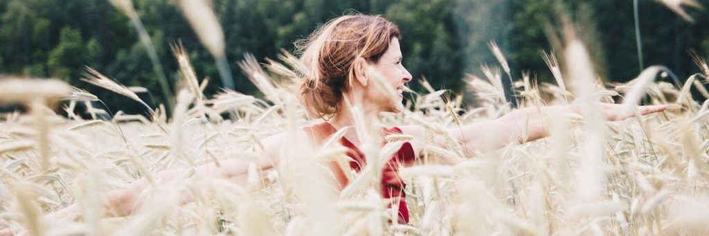woman stands in field happily smiling gratitude life loving herself