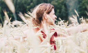 woman stands in field happily smiling gratitude life loving herself