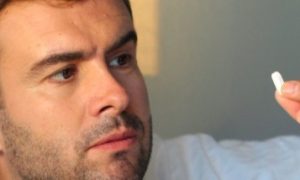 man looks at white tablet worrying about effectiveness of supplement