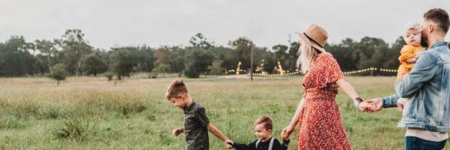 close knit happy family parents with three little adorable kids walking on green field
