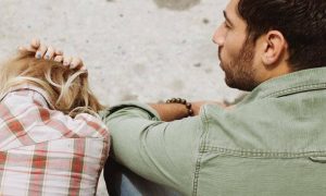 woman sits beside man scratching hair crying feeling depressed