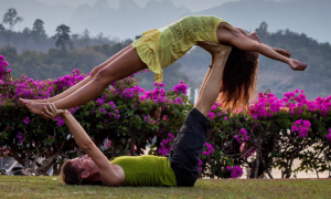 two women practice yoga in park beside lake mountain