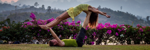 two women practice yoga in park beside lake mountain