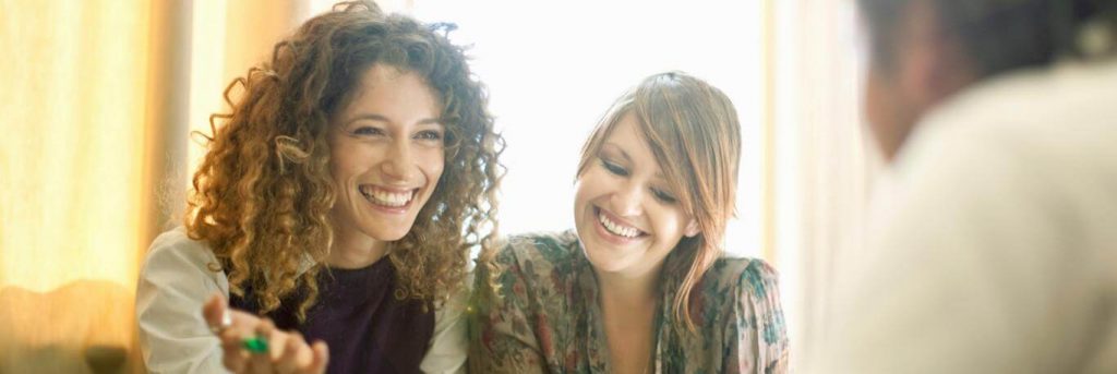 two women sits happily respectfully talking smiling at man